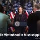 Fostoria News Kamala Harris speaking at a press conference with American flags behind her.